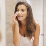 Beautiful brunette woman removing makeup from her face